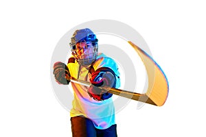 Motivation to win. Young girl, hockey player in helmet and uniform, training, playing against white background in neon