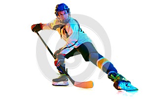 Motivation to win. Young girl, hockey player in helmet and uniform, training, playing against white background in neon