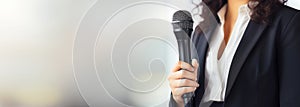 Motivational female speaker with microphone speaking on stage, banner format