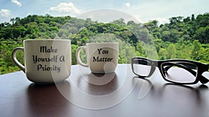 Motivational and inspirational quote on coffee cups - Make yourself a priority and you matter. Glasses and blurred