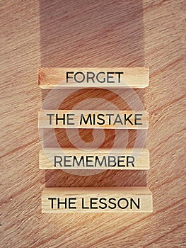 Motivational inspirational quote. Forget the mistake, remember the lesson text on wooden blocks background. Stock photo.