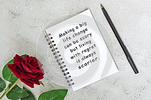 Motivational and inspirational quote on a note book with roses on a desk.