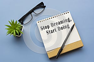 Motivational and inspirational quote on notepad - Stop dreaming, start doing.