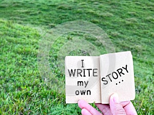 Motivational and inspirational quote - â€˜ I write my own storyâ€™ on notepad. Text with green background.
