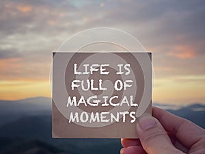 Motivational and inspirational wording. Life Is Full Of Magical Moments written on a notepad. With blurred styled background.