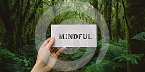 Motivational inspiring hand holding word card mindful in woods