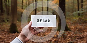 Motivational inspiring hand holding word card relax in woods