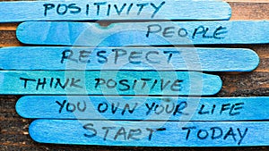 Motivational messages painted on blue wooden popsicle sticks against a rustic background