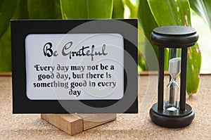 Motivational quote text on notepad with minutes glass.