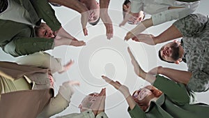 motivational training, young men and women put their hands together in circle then clap each other raising team spirit