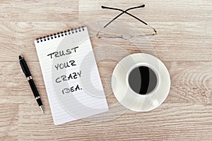 Motivational - Trust your crazy idea text on note pad on top of wood desk