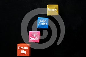 Motivational words on blackboard - Dream Big. Set Goals. Take Action. Succeed. With colorful origami paper craft.