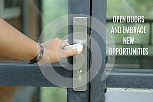Motivational words on door glass - Open doors and embrace new opportunity. With a person holding door handle, entering the door.