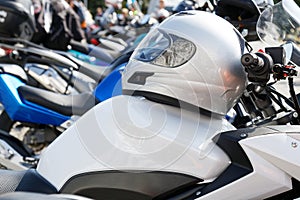 Moto helmet lies on the gas tank of a motorcycle and motorbikes on blurred background.