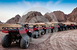 Moto safari in the desert a row of red ATVs on a halt against the background of rocky mountains and a blue sky Egypt