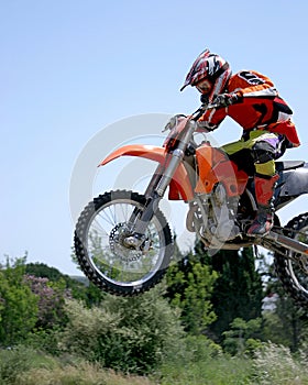 Motociclo saltando attraverso l'aria sul caldo soleggiato cielo blu 