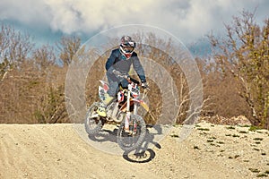 Motocross driver in action accelerating the motorbike after the corner on the race track