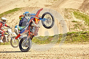 Motocross driver in action accelerating the motorbike takes off and jumps on springboard on the race track.