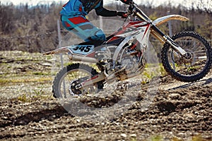 Motocross driver in action accelerating the motorbike takes off and jumps on springboard on the race track.