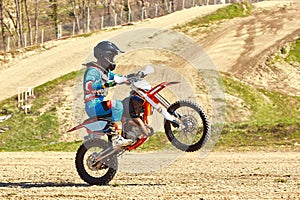 Motocross driver in action accelerating the motorbike takes off and jumps on springboard on the race track.
