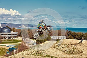 Motocross driver in action accelerating the motorbike takes off and jumps on springboard on the race track.