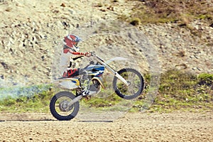 Motocross driver in action accelerating the motorbike takes off and jumps on springboard on the race track.