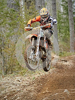 Motocross driver jumping with the bike at high speed on the race track