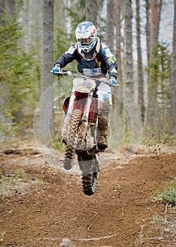 Motocross driver jumping with the bike at high speed on the race track