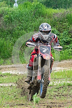 Motocross. A motorcyclist on one wheel rushes along a dirt road, dirt flies from under the wheels.