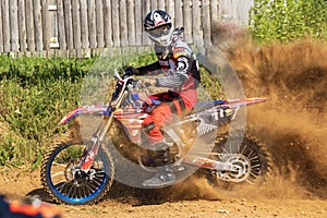 Motocross. Motorcyclist rushes along a dirt road, dust flies from under the wheels.