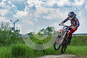 Motocross. Motorcyclist rushes along a dirt road.  Greenery in the foreground.