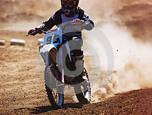 Motocross racer accelerating in dust track