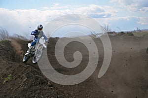 Motocross racer moves along sandy parapet turning track