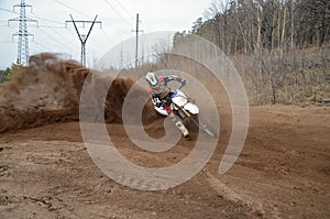 Motocross racer moves along sandy parapet turning track