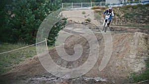 Motocross racer mxgirl on dirt bike jumping on track in rapid shoot, close up, Slow motion