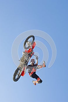 Motocross Racer Performing Stunt In Midair Against Blue Sky