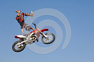 Motocross Racer Performing Stunt With Motorcycle In Midair Against Sky