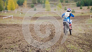 Motocross racer start riding his dirt Cross MX bike - rear view