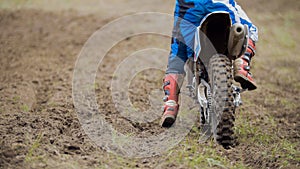 Motocross racer start riding his dirt Cross MX bike - rear view