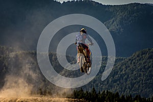 Motocross rider jumping in the air. Alps mountains in background