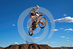 a motocross rider mid-jump against a clear blue sky