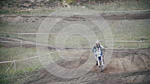 Motocross rider in a red jumpsuit chasing racer mxgirl on dirt bike on track in rapid shoot, Slow motion, close up