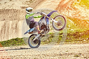 Motocross, a rider stands on the rear wheel of a bike, Riding on the rear wheel. Extreme, industrial, motorcycle cross