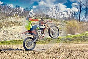 Motocross, a rider stands on the rear wheel of a bike, Riding on the rear wheel. Extreme, industrial, motorcycle cross