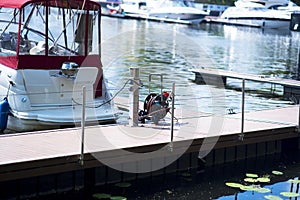 Motor boat anchored on a rope at the pier against the background of blurry yachts