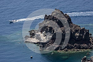 Motor boat and bathers off island at Oia, Santorini