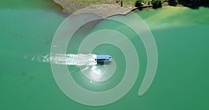 A motor boat with a canopy floats on a lake with clear water