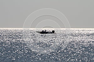 A motor boat is floating on the sea on the horizon.The reflection of the sun on the waves.Infinite ocean.