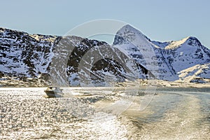 Motor boat in the middle of Nuuk fjord with frozen rocks in the background, Greenland