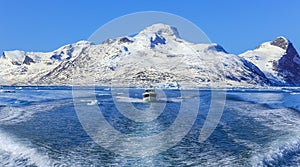 Motor boat in the middle of Nuuk fjord with frozen rocks in the background, Greenland